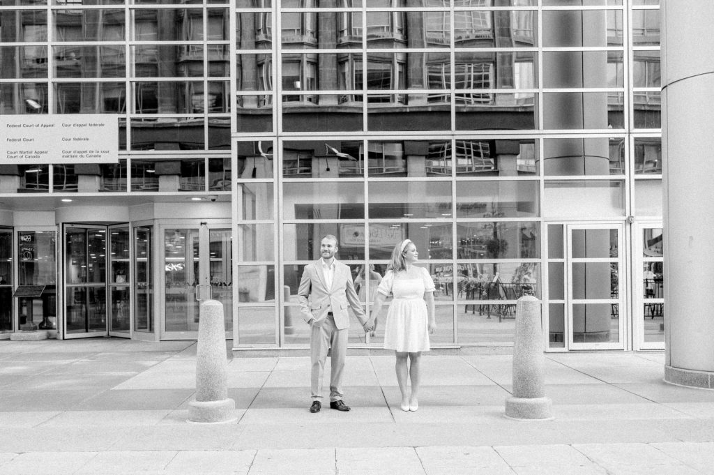 Couple holding hands outside the Federal Court of Appeal on Sparks Street, Ottawa, in black and white.