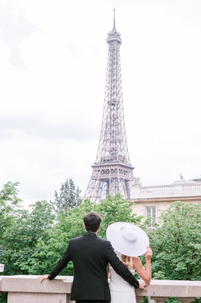 Couple embracing on a bridge overlooking the Eiffel Tower, in Paris.