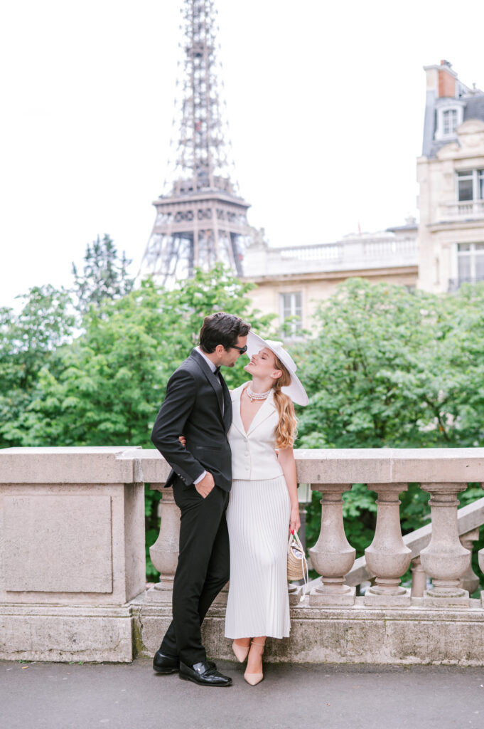 Bride and groom sharing a moment on a stone balustrade bridge with the Eiffel Tower in the background, in Paris.