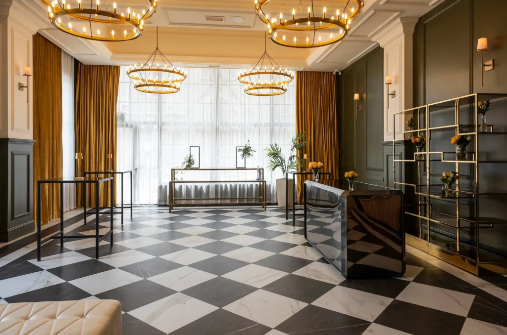 Trillium Room at the Lord Elgin Hotel featuring a checkered marble floor, gold ring chandeliers, mustard velvet curtains, and dark green paneled walls.