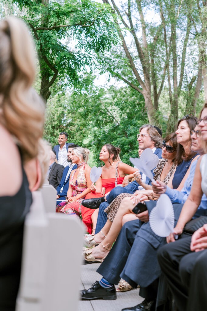 Guests seated and watching a ceremony beneath shady trees at Stonefields Estate.