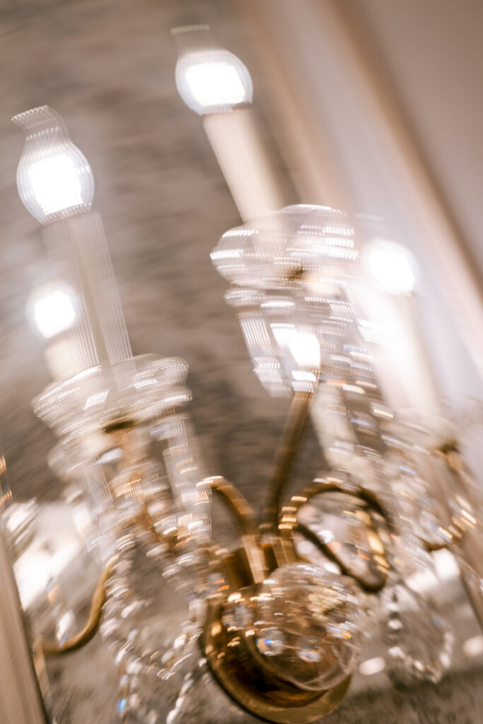 Close-up blurred shot of a crystal chandelier at the Fairmont Royal York, highlighting its glowing bulbs and ornate brass scrollwork.