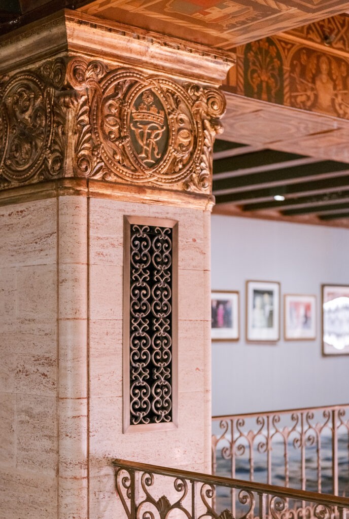 Carved stone column detail at the Fairmont Royal York, featuring an ornate crest medallion and decorative ironwork grille above a mezzanine railing.