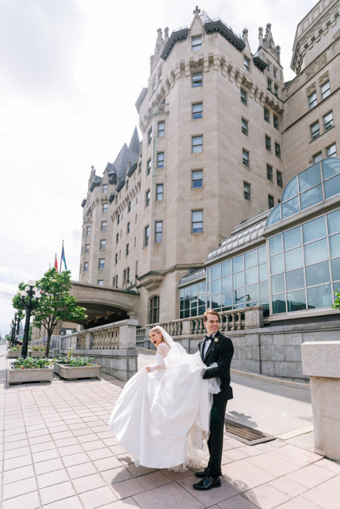 Bride and groom posing outside a grand château-style hotel with turreted stone architecture.