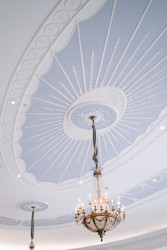 Ornate domed ceiling with radiating molded plasterwork and a brass chandelier, styled by Erica Irwin Weddings & Events.