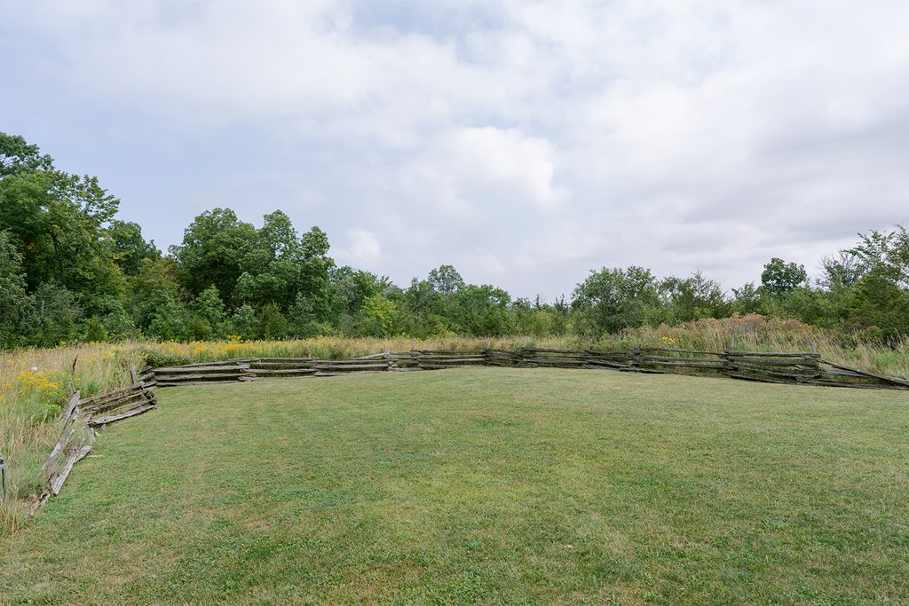 Open lawn bordered by a split-rail fence and wildflower meadow at Compass Rose, a Prince Edward County wedding venue